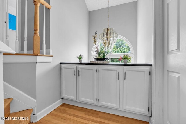 detailed view of wood finished floors, baseboards, and a chandelier