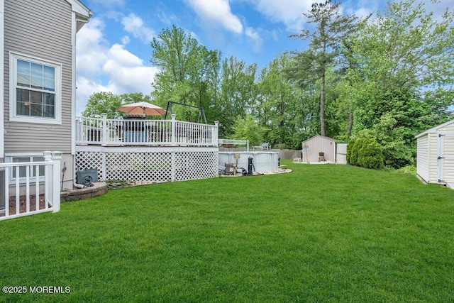 view of green lawn with a storage unit, a deck, and an outdoor structure