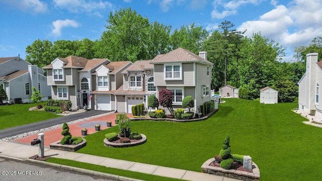 view of front of home featuring driveway, a garage, a chimney, a front lawn, and a residential view