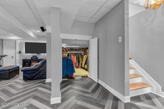 finished basement with baseboards, a drop ceiling, stairway, and recessed lighting