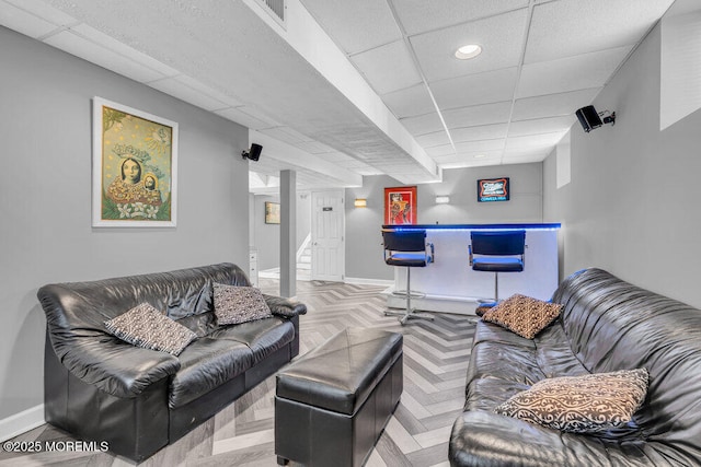 living room with a bar, baseboards, a paneled ceiling, and recessed lighting
