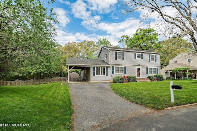colonial-style house with a shed, a chimney, driveway, an outdoor structure, and an attached carport