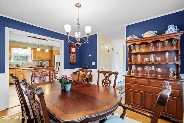 dining room with a chandelier, light wood finished floors, and wainscoting