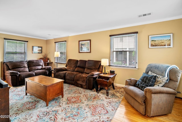 living area featuring wood finished floors, crown molding, plenty of natural light, and baseboards