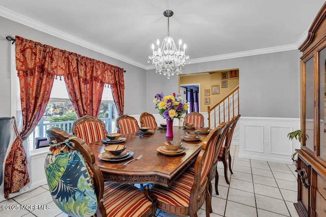 dining area featuring a chandelier, light tile patterned floors, crown molding, stairs, and wainscoting