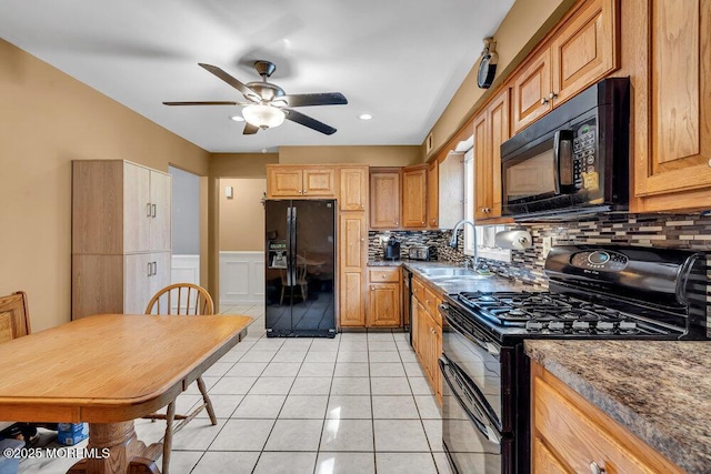 kitchen with black appliances, a sink, a ceiling fan, decorative backsplash, and wainscoting