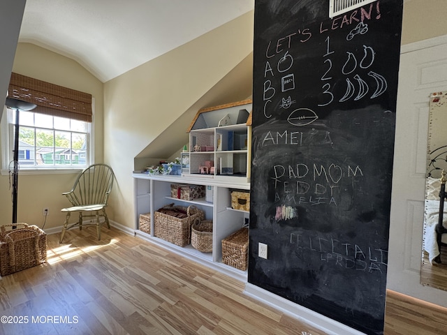 sitting room with wood finished floors, vaulted ceiling, and baseboards