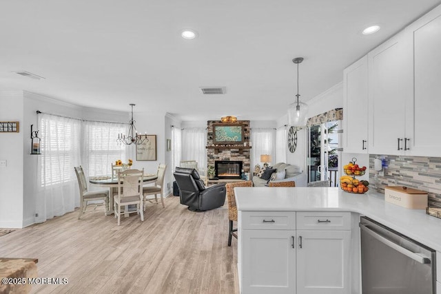 74 Dock Rd, Brick, NJ 08723 - kitchen with stainless steel dishwasher, a stone fireplace, a peninsula, white cabinets, and light countertops