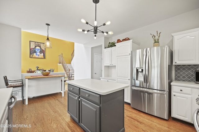 kitchen with stainless steel appliances, white cabinetry, and light wood-style flooring