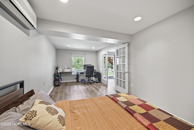 bedroom with a wall mounted AC, french doors, wood finished floors, a desk, and recessed lighting