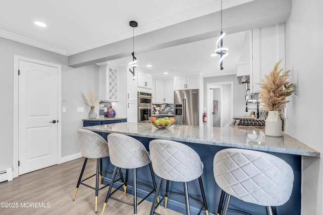 3 Toledo Dr, Brick, NJ 08723 - kitchen featuring appliances with stainless steel finishes, a peninsula, white cabinets, light wood-style floors, and tasteful backsplash