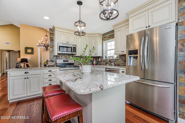 178 Loganberry Ln, Freehold, NJ 07728 - kitchen with stainless steel appliances, a chandelier, cream cabinetry, a peninsula, and dark wood-style flooring
