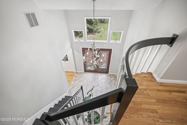 entrance foyer with stairs, a chandelier, baseboards, and wood finished floors