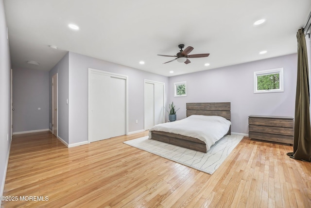 bedroom with two closets, light wood-type flooring, baseboards, recessed lighting, and a ceiling fan