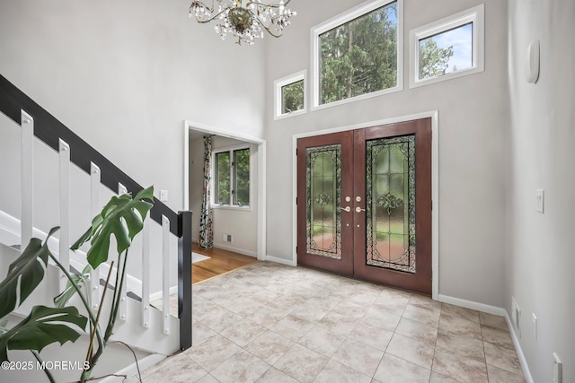 foyer entrance featuring a chandelier, plenty of natural light, french doors, stairs, and a high ceiling