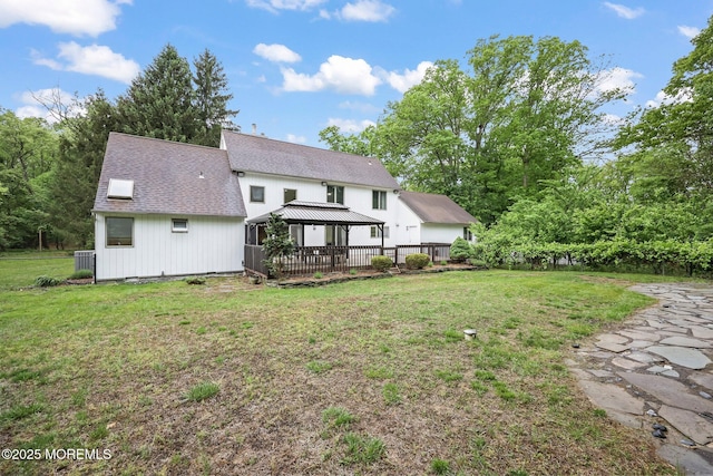 back of house with a gazebo, a lawn, and a shingled roof