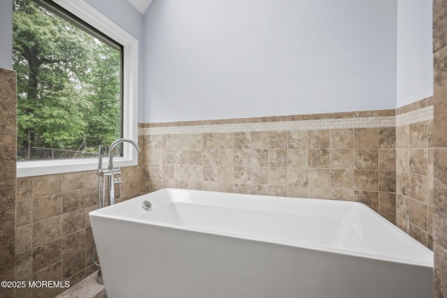 bathroom featuring a soaking tub and tile walls