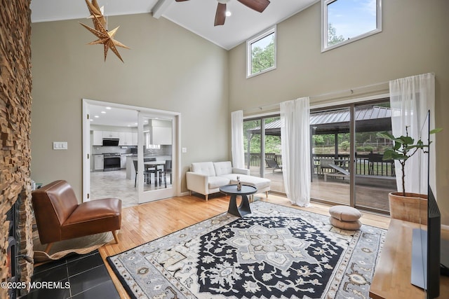 living room featuring high vaulted ceiling, a ceiling fan, beamed ceiling, and plenty of natural light