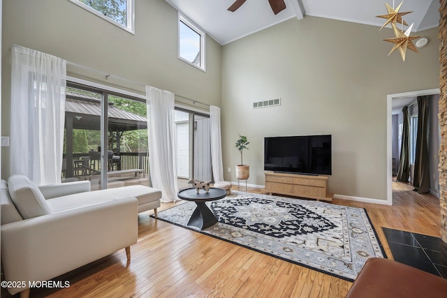 living area with high vaulted ceiling, hardwood / wood-style floors, plenty of natural light, beamed ceiling, and baseboards