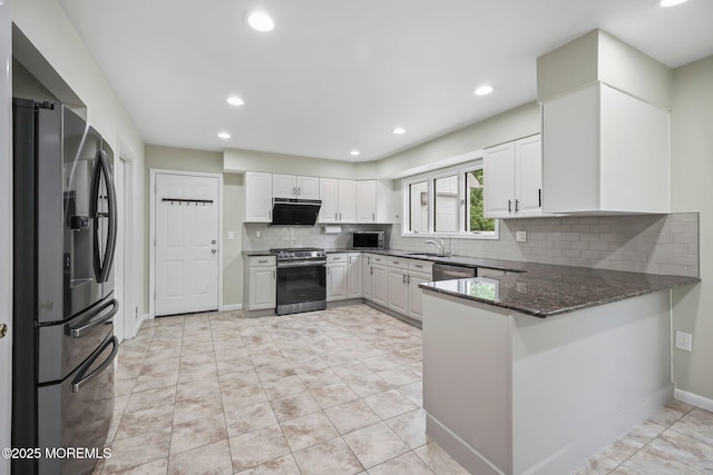 kitchen with stainless steel appliances, a peninsula, baseboards, decorative backsplash, and a sink