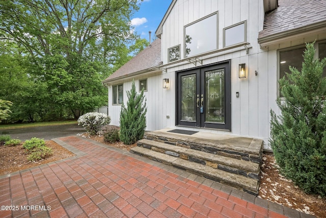 view of exterior entry with a shingled roof and french doors