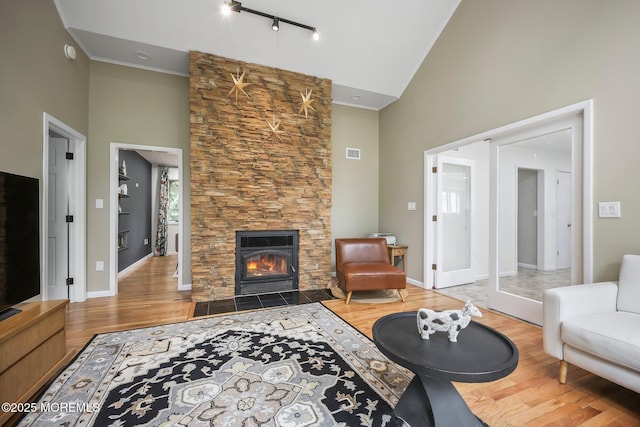living room with high vaulted ceiling, wood finished floors, a fireplace, and baseboards