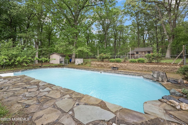 view of pool featuring an outdoor structure, fence, and a storage unit