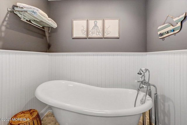 bathroom with wainscoting and a soaking tub