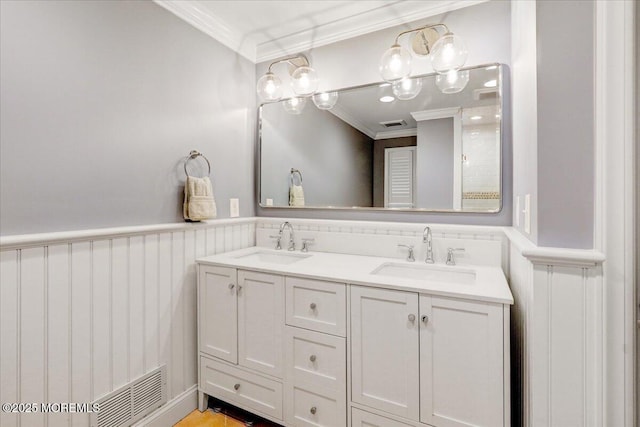 bathroom featuring ornamental molding, wainscoting, and double vanity