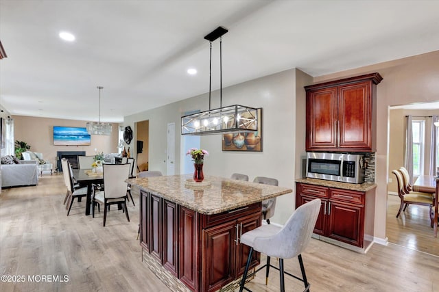 1041 Aumack Rd, Jackson, NJ 08527 - kitchen with stainless steel microwave, dark brown cabinets, light wood-type flooring, a breakfast bar, and a center island