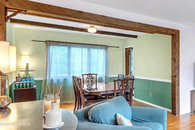dining space featuring beamed ceiling, wood finished floors, and baseboards