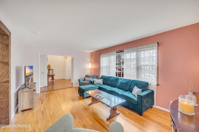 living area featuring light wood-type flooring, a chandelier, and baseboards