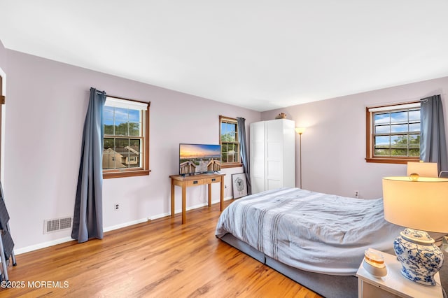 bedroom featuring light wood finished floors, multiple windows, and baseboards