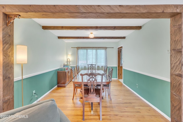 dining area with light wood finished floors, baseboards, and beamed ceiling