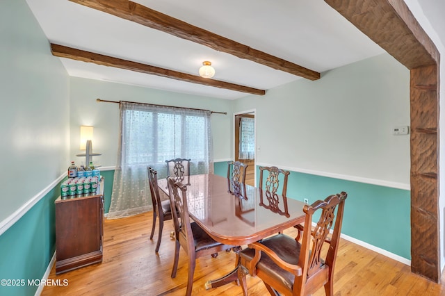 dining room with baseboards, beam ceiling, and wood finished floors