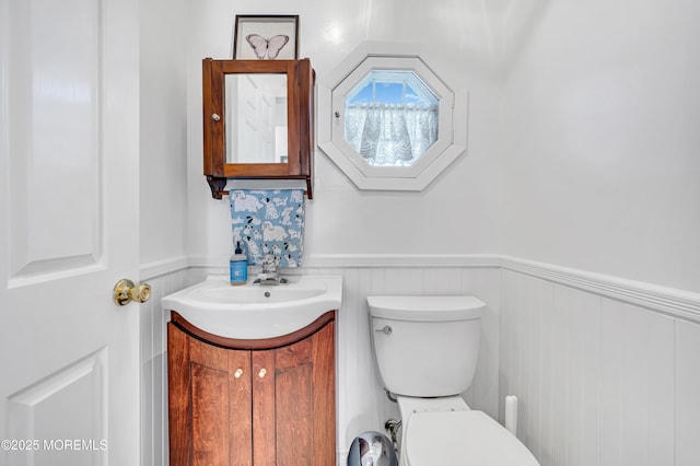 half bath featuring wainscoting, vanity, and toilet