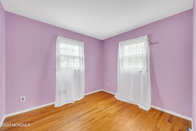 empty room with plenty of natural light, baseboards, and light wood-style flooring
