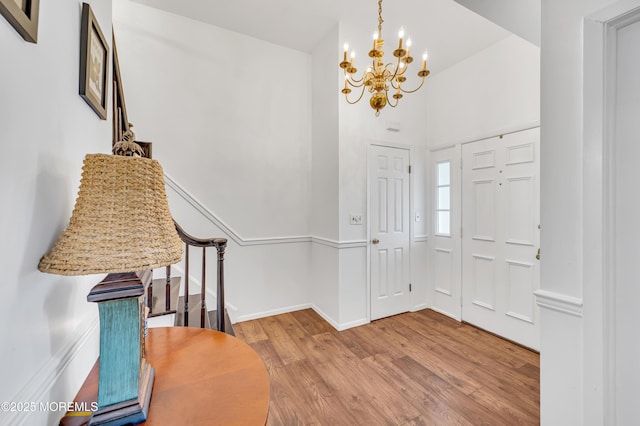 foyer entrance featuring a chandelier, wood finished floors, and baseboards