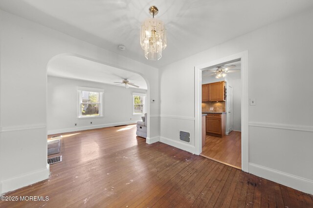 unfurnished room featuring arched walkways, ceiling fan, and hardwood / wood-style flooring