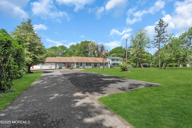 view of front of house featuring a front yard, asphalt driveway, and an attached garage