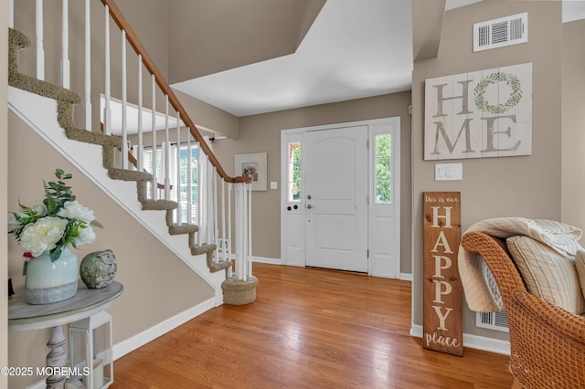 foyer entrance with wood finished floors, stairs, and baseboards