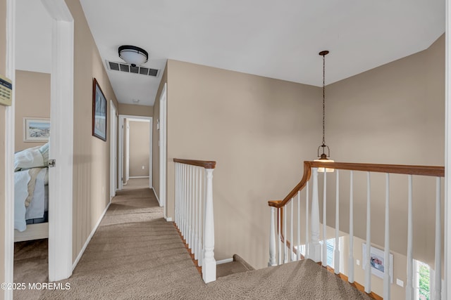 hall featuring an upstairs landing, carpet, and baseboards