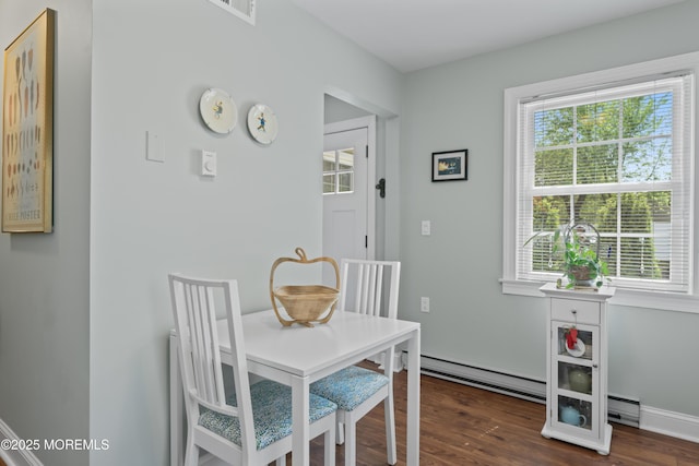 dining space featuring a baseboard heating unit, dark wood-type flooring, and baseboards