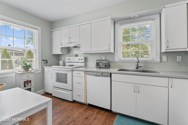 kitchen featuring white appliances, under cabinet range hood, a sink, dark wood-style floors, and tasteful backsplash
