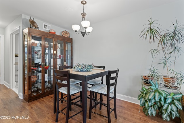 dining space featuring wood finished floors, a chandelier, and baseboards