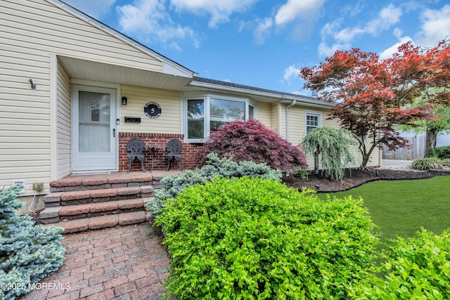 property entrance with brick siding and a yard