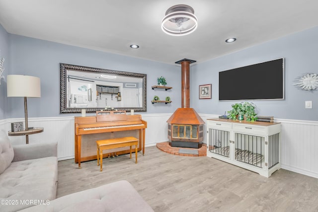 living room with wainscoting, a wood stove, and wood finished floors