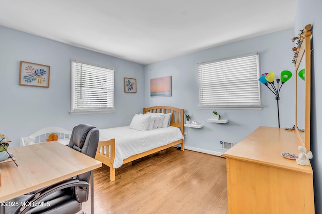 bedroom featuring multiple windows, light wood-type flooring, and baseboards
