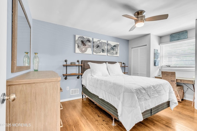 bedroom with baseboards, wood finished floors, a ceiling fan, and a closet