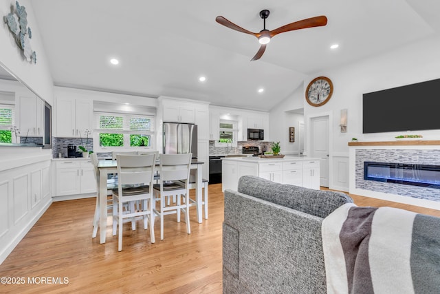 living area featuring lofted ceiling, a ceiling fan, a tile fireplace, light wood finished floors, and recessed lighting